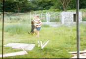 Wilcommen, No. 0018 A Young White Man In Striped Shirt and Jorts Plays With a German Shepherd